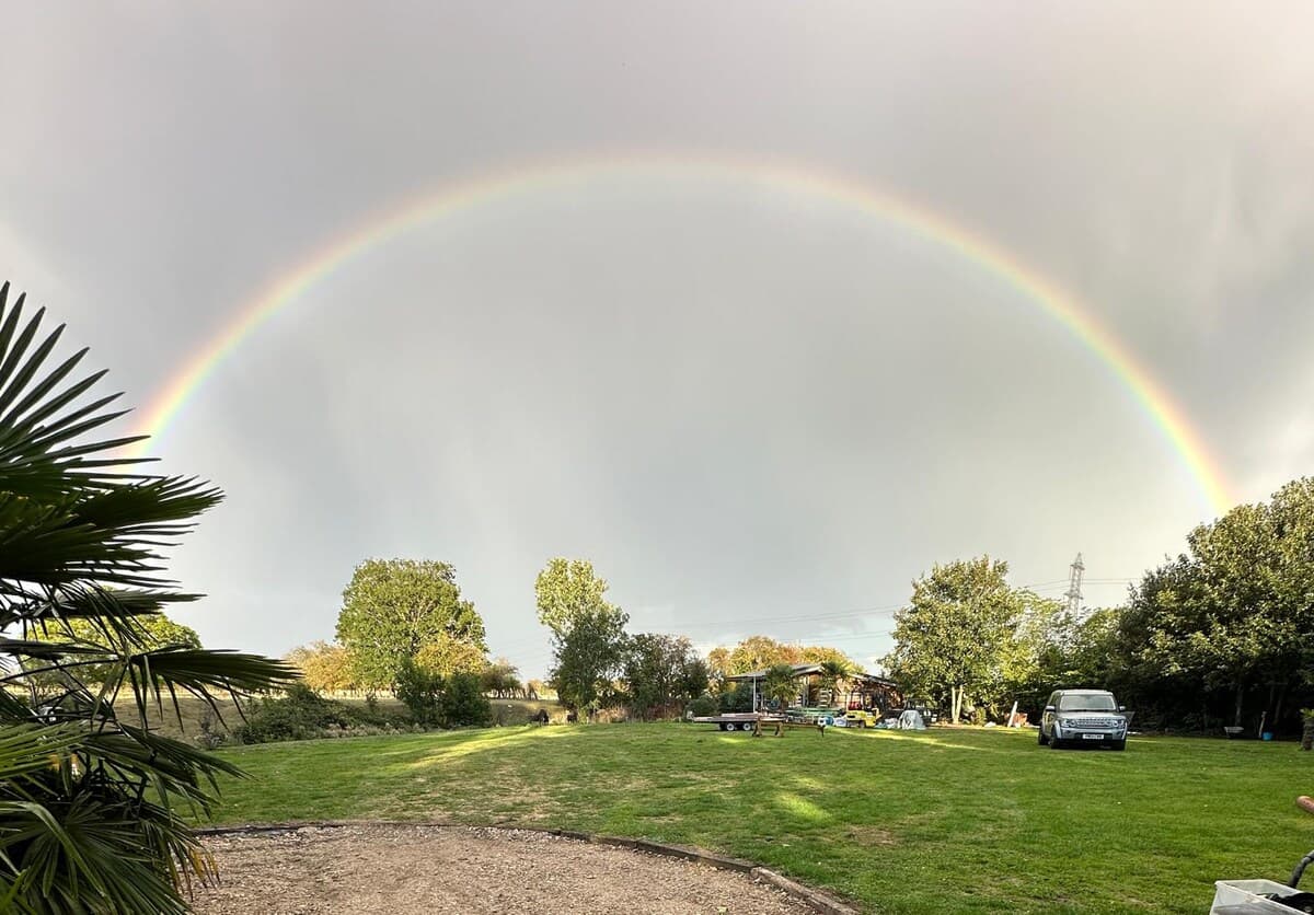 Spacious grounds with rainbow arc overhead, offering peaceful countryside views and room to explore at Scarthingmoor House Farm.